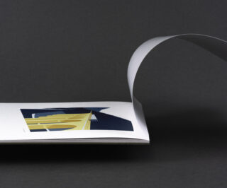 Ein minimalistisches Bild eines offenen Buches, bei dem eine einzelne Seite umgeblättert wird und die Illustration einer gelben Brücke auf dunklem Hintergrund zeigt.