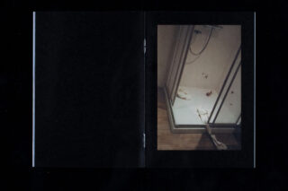 Eine Duschkabine mit Glastür, Seidenpapier auf dem Boden und im Inneren sowie kleinen rötlichen Flecken auf der Duschwanne.