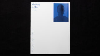 Ein weißes Buchcover mit dem Titel „Meeting A Man“ zeigt den Namen eines Autors und ein blau getöntes, verschwommenes Porträt einer Person in der oberen rechten Ecke. Der Text ist außerdem am linken Rand ausgerichtet.