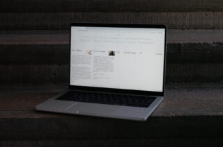 Auf Betonstufen steht ein Laptop, auf dem eine Website mit Texten und Kategorien zu Artikeln, Produkten und Design angezeigt wird.