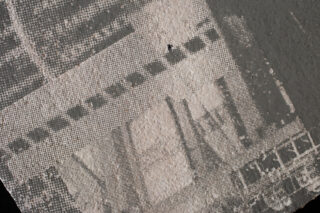 Nahaufnahme einer strukturierten, pixeligen Oberfläche, auf der das Wort „YEAH“ in Blockbuchstaben angezeigt wird, teilweise umgeben von schwarzen Punkten und geometrischen Mustern.