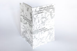 Ein weißes Buch mit abstrakten grauen Mustern auf dem Einband und teilweise sichtbarem schwarzem deutschen Text, aufrecht stehend auf weißem Hintergrund.