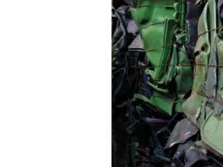 Gestapelte, zerdrückte grüne Autoteile, die mit Draht zusammengebunden sind, nehmen die rechte Seite des Bildes ein; die linke Seite ist völlig leer und weiß.