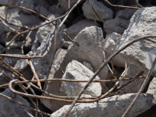 Zerbrochener Betonschutt mit freiliegendem, verrostetem Bewehrungsstahl, verstreut auf einem Haufen.