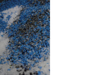 Eine Nahaufnahme eines Haufens kleiner blauer, schwarzer und weißer Kunststoffgranulate oder -pellets.