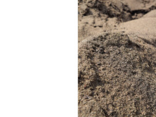 Eine Nahaufnahme eines Hügels aus braunem Sand auf der rechten Seite, wobei die linke Seite des Bildes leer und weiß ist.