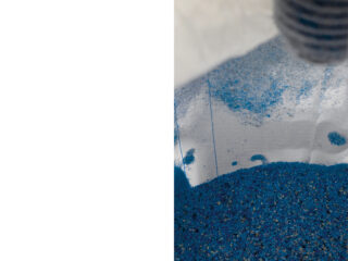 Eine Nahaufnahme von blauem Granulat, das in der Ecke eines weißen, halbtransparenten Beutels gesammelt wurde.