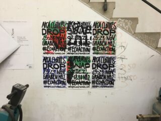 Eine Wand mit mehreren Veranstaltungsplakaten im Graffiti-Stil in verschiedenen Farben, die für Kleiderabgaben und Öko-Aktionsveranstaltungen werben, neben Industrieanlagen und einer mit Graffiti besprühten Treppe.