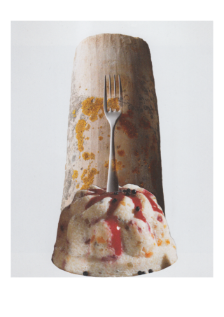 Eine silberne Gabel steht aufrecht in einem Dessert mit Soße und Beeren, positioniert vor einem großen, strukturierten, zylindrischen Objekt.