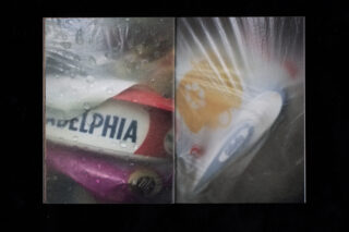 Eine Nahaufnahme verschiedener verpackter Lebensmittel, darunter ein Behälter mit Philadelphia-Frischkäse, gesehen durch eine neblige, nasse Plastikoberfläche.