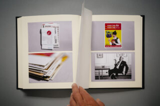 Eine Hand blättert in einem Fotobuch, das Bilder von Eintrittskarten, Dokumenten, einem Protestplakat und einer Person zeigt, die an einem Schreibtisch sitzt.