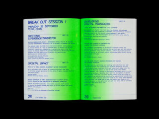 Ein offenes Buch zeigt einen Zeitplan und Beschreibungen für Breakout-Sitzungen zu digitaler Pädagogik und Technologie, mit blauem und grünem Text auf den weißen Seiten mit den Nummern 28 und 29.