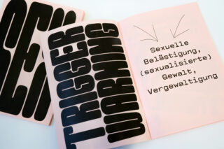 Offenes Buch mit dem fettgedruckten Text „TRIGGERWARNUNG“ und einem deutschen Warntext vor sexueller Belästigung, sexualisierter Gewalt und Vergewaltigung auf einer rosa Seite.