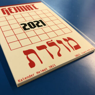 Ein Kalender für 2021 mit dem Titel „Heimat“ mit Text in Deutsch und Hebräisch auf blauem Grund. Die große Zahl „2021“ steht zentriert auf dem Cover.
