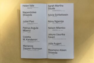 Ein aufgeschlagenes Heft zeigt auf zwei Seiten eine Auflistung von Namen, Zeiten und Rollen in einer klaren serifenlosen Schriftart auf gelbem Untergrund.