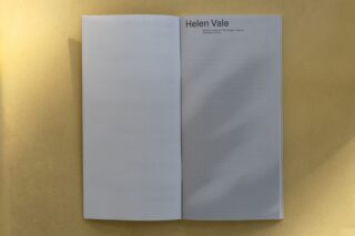 Ein aufgeschlagenes Buch auf gelbem Untergrund zeigt eine weitgehend leere rechte Seite mit der Überschrift „Helen Vale“ in der oberen rechten Ecke. Die linke Seite ist schwach durch das Buch hindurch sichtbar.