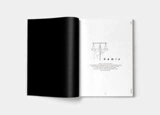 Eine aufgeschlagene Zeitschrift zeigt eine überwiegend schwarze linke Seite und eine rechte Seite mit minimalem Text, einer Strichzeichnung von über einer Hand hängenden Lichtern und dem Wort „Hemis“ in Kleinbuchstaben.