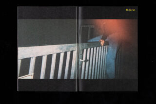 Eine Person mit einer Hand auf einem Metalltor in der Nacht, teilweise verdeckt durch rotes Licht, mit einem Zeitstempel „04:32:42“ in der oberen rechten Ecke.