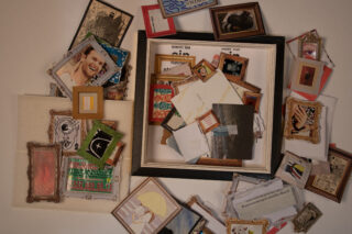 Eine Sammlung verschiedener gerahmter Fotos, Zeichnungen, Ausschnitte und Umschläge, die um und in einem leeren Bilderrahmen auf weißem Hintergrund angeordnet sind.