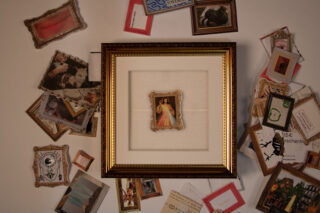 Mehrere Bilderrahmen, im Vordergrund ein größerer Bilderrahmen mit einem religiösen Bild in der Mitte.