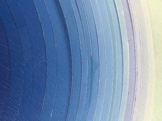 Nahaufnahme konzentrischer, strukturierter Ringe in Blau- und Hellvioletttönen, die allmählich von Dunkel zu Hell übergehen.