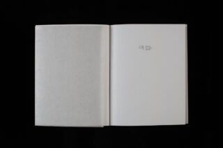 Ein offenes Buch mit einer größtenteils leeren rechten Seite, auf der in kleiner Schrift der Text steht: „6.30 Unentschieden, 7.41 Abendessen, 12.18 Zuhause“ auf schwarzem Hintergrund.