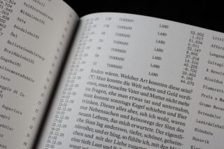 Nahaufnahme eines offenen Buches, das eine Tabelle mit Uhrzeiten und dem wiederholten Wort „Tornado“ zeigt, neben einem Textblock auf Deutsch auf der rechten Seite.