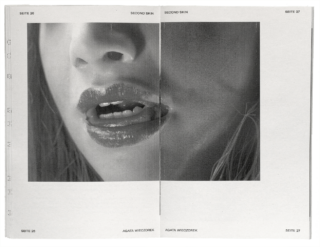 Nahaufnahme eines Schwarzweißfotos des teilweise geöffneten Munds einer Person mit sichtbaren Zähnen und glänzenden Lippen, über zwei Seiten eines Buches oder einer Zeitschrift gedruckt.