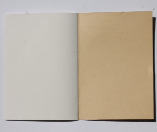 Ein offenes Notizbuch mit einer weißen Seite links und einer braunen Seite rechts, beide leer und unbeschriftet.