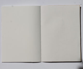 Ein offenes Notizbuch liegt flach auf einer weißen Oberfläche und zeigt zwei leere, unlinierte Seiten.