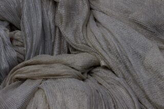 Nahaufnahme eines locker gefalteten, hellgrauen Netzgewebes mit sichtbarer Textur und feinen Fäden.