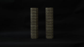 Zwei zylindrische Objekte mit komplizierten architektonischen Mustern stehen aufrecht vor einem dunklen Hintergrund.