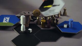 Verschiedene Brettspielsteine, Spielmarken und sechseckige Spielsteine sind auf einer Fläche angeordnet, wobei eine Hand eine Karte über der Gruppe hält.