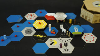 Ein Tischbrettspiel mit sechseckigen Spielsteinen, Holzfiguren, Karten und einer Holzkiste auf einer schwarzen Oberfläche, die in einem strategischen Layout angeordnet sind.