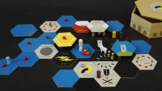 Ein Strategie-Brettspiel mit sechseckigen Spielsteinen, blauen und schwarzen Sechsecken, Holzstücken, Spielmarken und einer sechseckigen Holzkiste auf einer schwarzen Oberfläche.