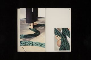 Eine Person steht auf einem gefliesten Boden, zu ihren Füßen liegt ein dickes, grünes geflochtenes Seil; auf der rechten Seite hält eine andere Hand dasselbe Seil.