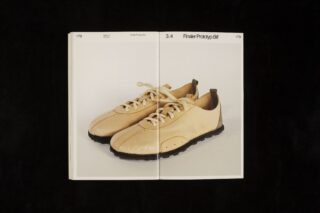 Ein Paar beige Schnürschuhe mit dunklen Sohlen ist auf den Seiten eines offenen Buches vor einem schlichten Hintergrund abgebildet.