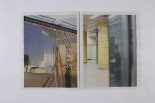 In einer aufgeschlagenen Zeitschrift sind zwei Fotos zu sehen: Auf der linken Seite sind Gebäudespiegelungen auf Glas zu sehen, während auf der rechten Seite eine verschwommene U-Bahn-Szene mit gelb gekachelten Säulen zu sehen ist.