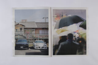 In einer aufgeschlagenen Zeitschrift sind zwei Fotos zu sehen: eines von geparkten Autos vor Häusern und eines von Menschen mit Regenschirmen in einer Menschenmenge.