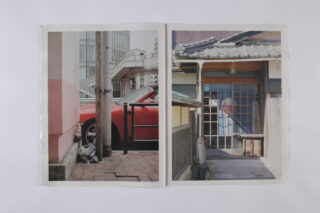 In einem offenen Buch sind zwei Fotos zu sehen: ein rotes Auto, das neben einem Strommast geparkt ist, und ein Gebäude mit einem „Geschlossen“-Schild an einem Holztor.