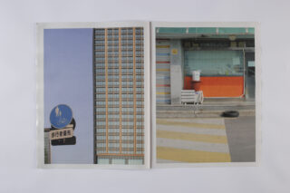 Offenes Buch mit zwei Fotos: links ein blaues Fußgänger- und Fahrradschild mit einem hohen modernen Gebäude; rechts eine geschlossene Ladenfront mit orangefarbener Tafel und einem einzelnen Reifen auf einem Zebrastreifen.