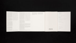 Auf einem schwarzen Hintergrund ist ein gefaltetes weißes Blatt Papier aufgeschlagen, auf dem in Spalten gedruckter Text und in der Mitte in fetten Buchstaben der Satz „ICH BIN DABEI“ zu sehen ist.