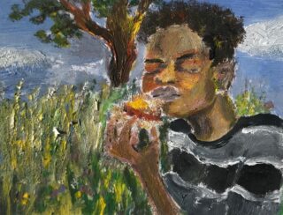 Eine Person mit lockigem Haar und einem schwarz-weißen Hemd schließt die Augen, während sie auf einer Wiese mit einem Baum im Hintergrund Obst isst.