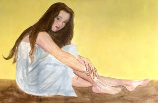 Eine Frau mit langen braunen Haaren sitzt auf dem Boden, ein weißes Tuch um sie herum, vor einem schlichten gelben Hintergrund.