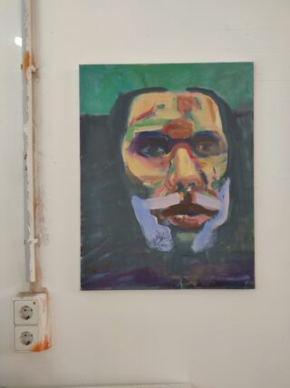 Abstraktes Gemälde eines menschlichen Gesichts mit kräftigen, bunten Pinselstrichen auf dunklem Hintergrund; angezeigt auf einer weißen Wand über Steckdosen.