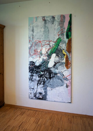 Abstraktes Gemälde mit kräftigen Pinselstrichen und Kritzeleien in Schwarz, Rot, Grün, Braun und Grau, angebracht an einer weißen Wand in einem Raum mit Holzboden und einem Holzschrank.