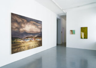 Eine Galerie für zeitgenössische Kunst mit drei abstrakten Gemälden auf weißen Wänden und einem polierten grauen Boden, beleuchtet mit natürlichem und künstlichem Licht.