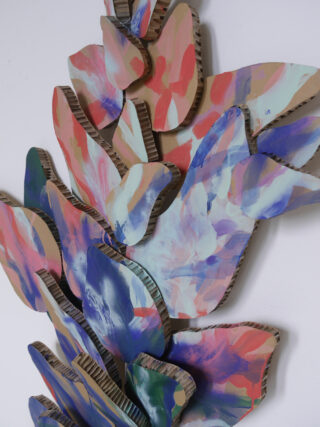 Übereinandergeschichtete Pappausschnitte, die mit bunten, abstrakten Pinselstrichen bemalt sind, sind in einem überlappenden Muster vor einem weißen Hintergrund angeordnet.