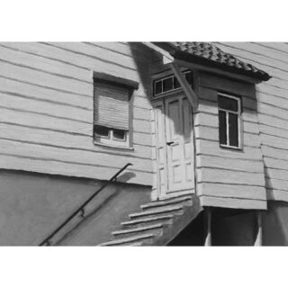 Schwarzweißbild eines Holzhauses mit einer Außentreppe, die zu einer Tür führt; an einem Fenster sind die Jalousien geschlossen, an einem anderen ist nichts zu sehen.