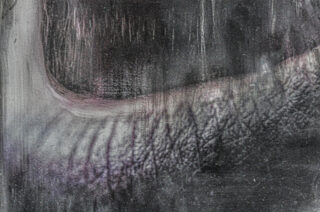 Nahaufnahme einer strukturierten Oberfläche mit rauen, sich kreuzenden Linien und einem schattierten, dunklen Bereich in der oberen linken Ecke.